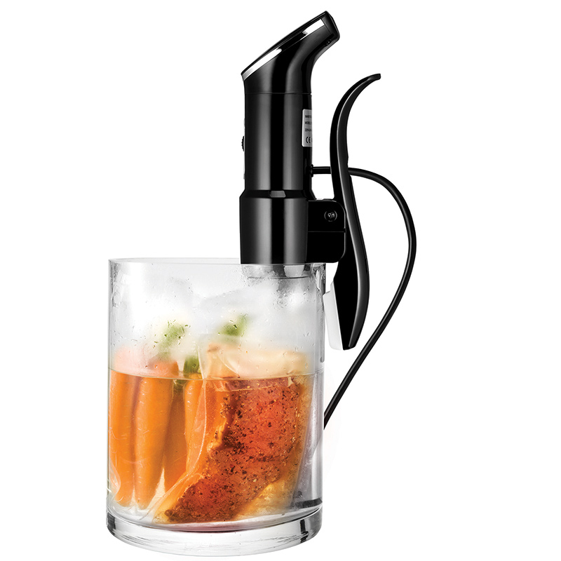 Schwarzer Immersion-Zirkulator in Glasbehälter mit Essen, orangefarbene und klare Flüssigkeit.
