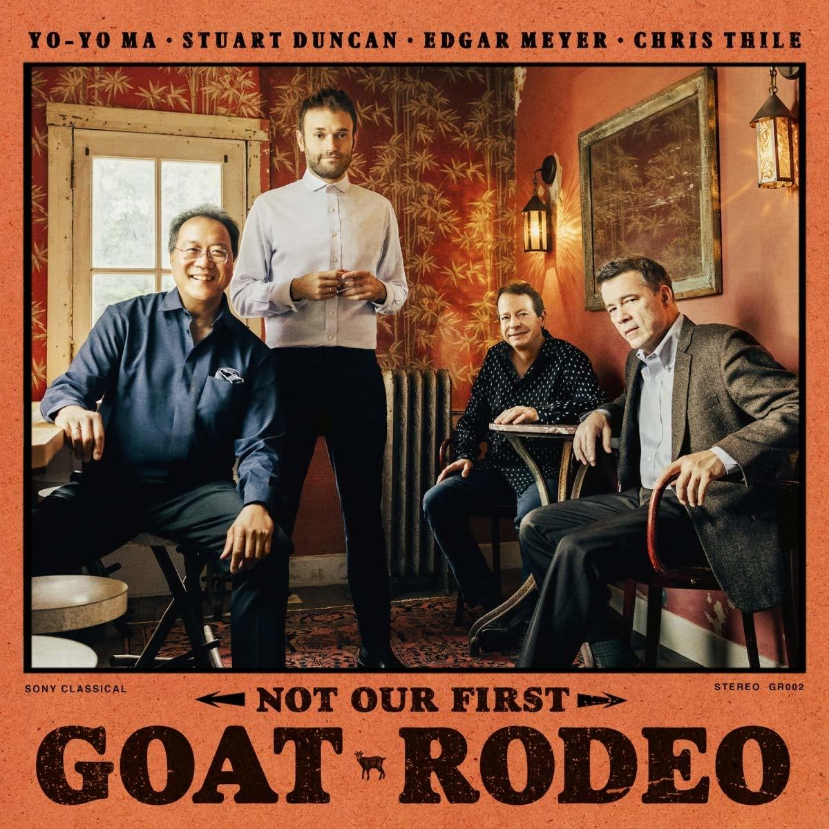 Négy férfi pózol egy zenekari fotóhoz. A zenekar neve Goat Rodeo. Egy festménnyel és tapétával rendelkező szobában vannak.