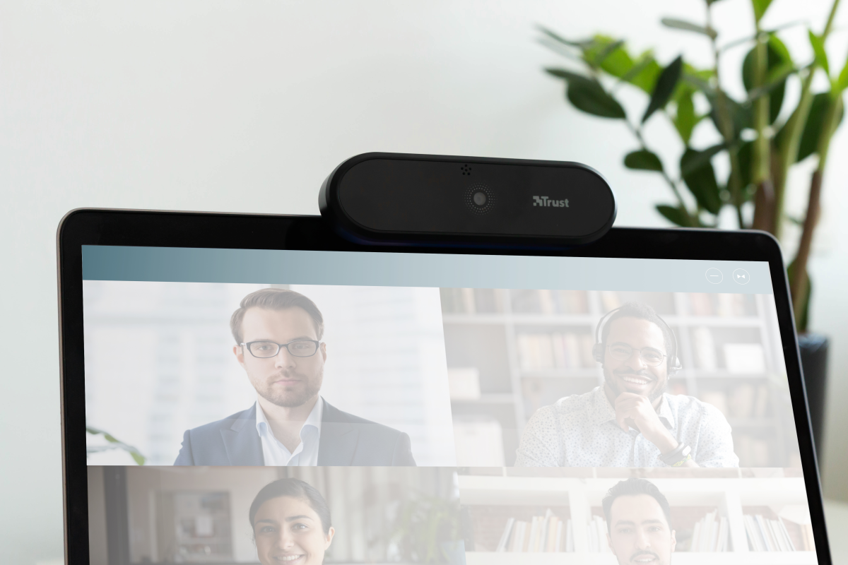 Laptop con webcam encima, videollamada en curso, entorno de oficina.