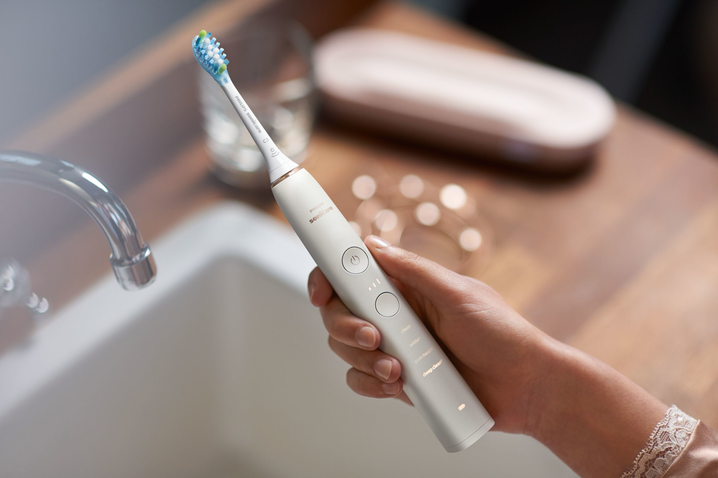 Person hält weiße und silberne Philips Sonicare Zahnbürste im Badezimmer.