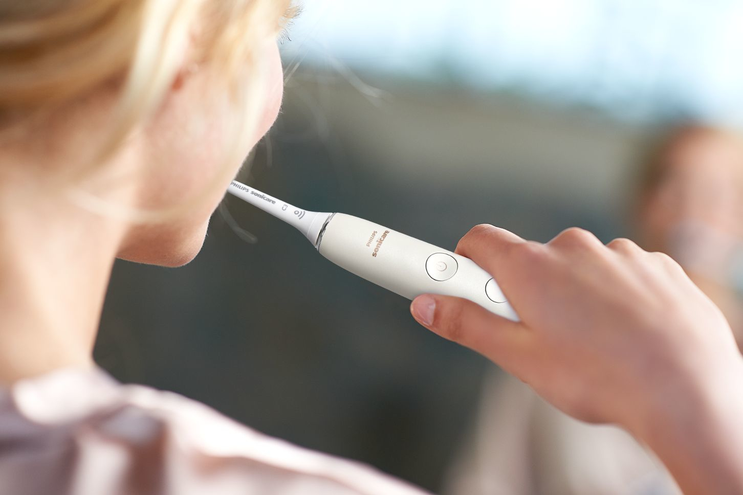 Eine Person putzt sich mit einer weißen Philips Sonicare elektrischen Zahnbürste die Zähne.