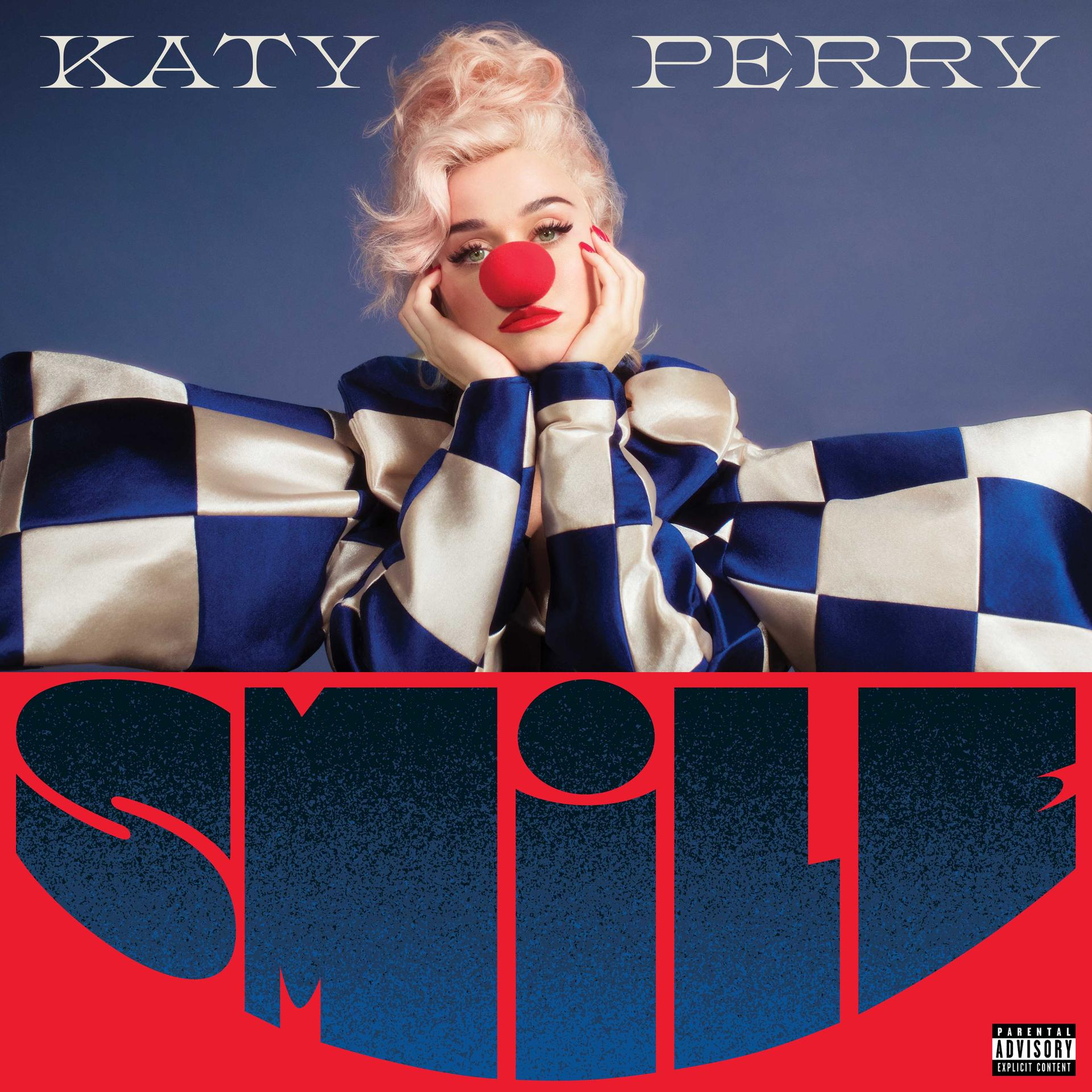 Pochette de l'album de Katy Perry. Elle porte une tenue de clown et un nez rouge. Le mot SMILE domine l'image.