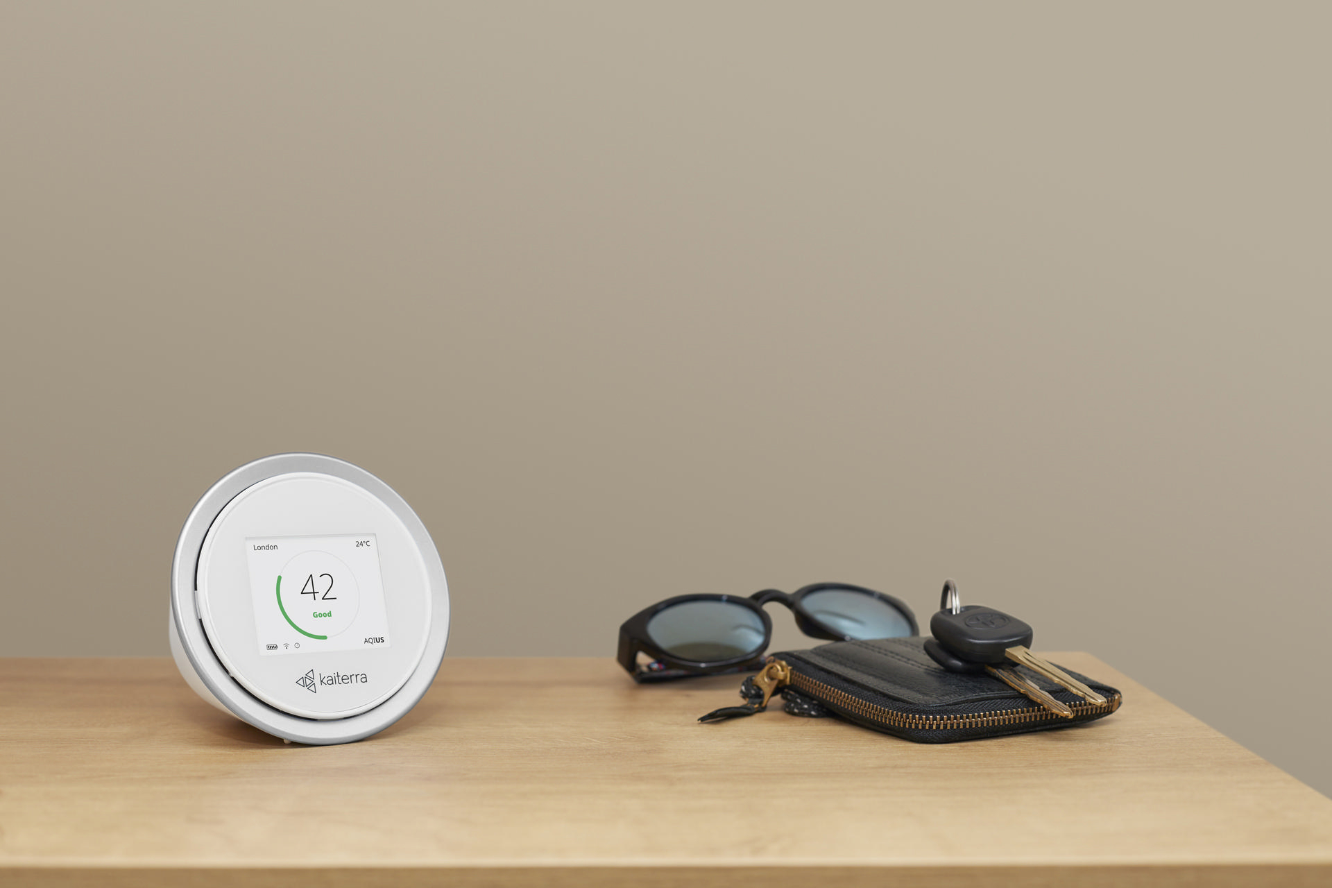 Weißes Smart Home-Gerät mit Bildschirm, Sonnenbrille, Schlüsseln und Brieftasche.