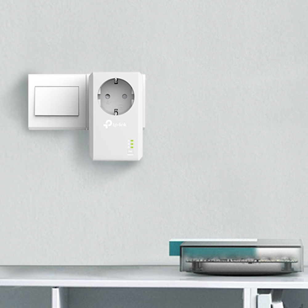 A white tp-link powerline adapter plugged into an outlet on a white wall. A switch is also present.