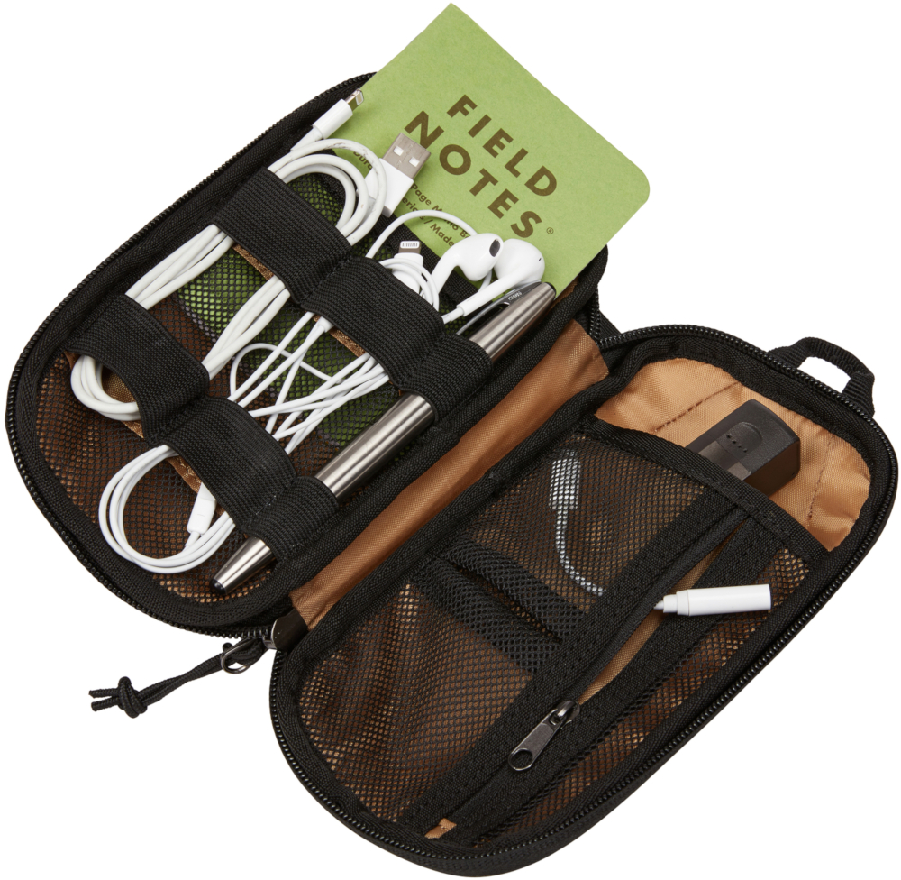 Trousse de voyage ouverte avec câbles, écouteurs, stylo et bloc-notes.
