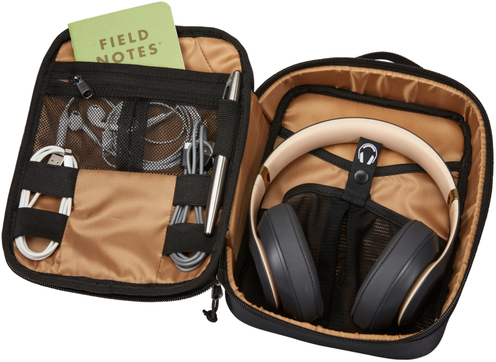 An open black travel case with headphones, cables, a pen, and a notepad.