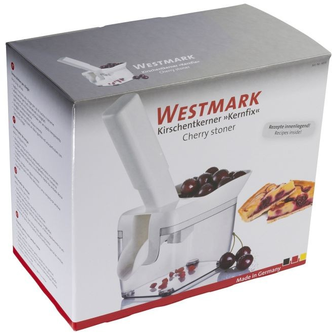 Egy 'WESTMARK' feliratú doboz cseresznyemagozónak. A doboz a készüléket és a cseresznyéket mutatja.