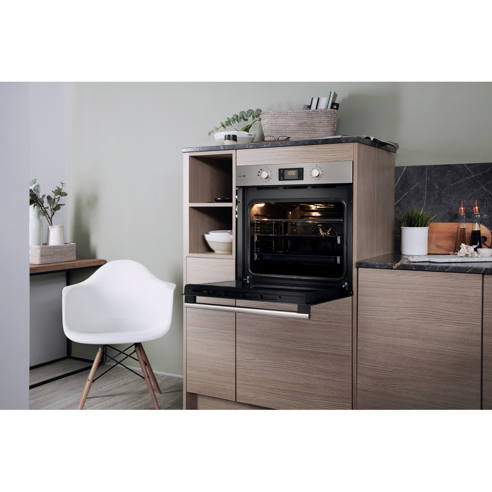 Küche mit offenem Backofen, weißem Stuhl, Holzschränken und Pflanzen auf der Theke.