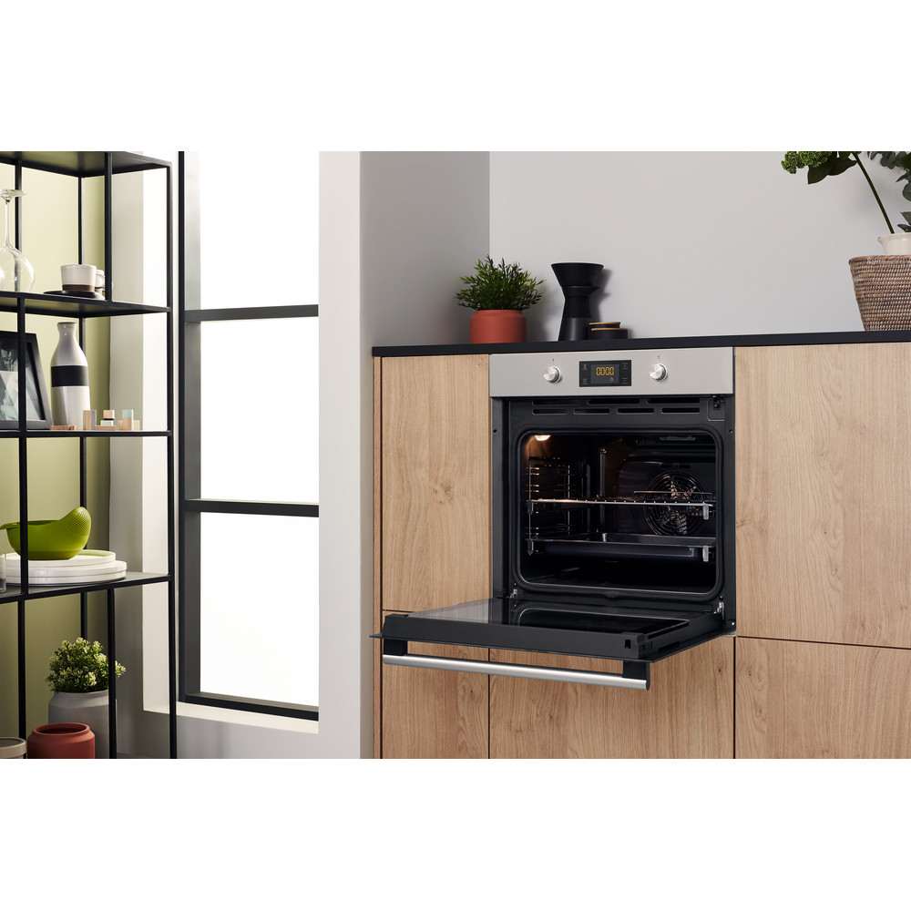 Küche mit Backofen und Holzschränken. Fenster im Hintergrund.