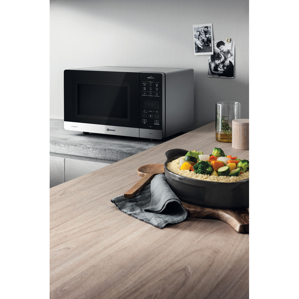 Mikrowelle auf einer hölzernen Arbeitsplatte, mit einer Schüssel Essen und Fotos.