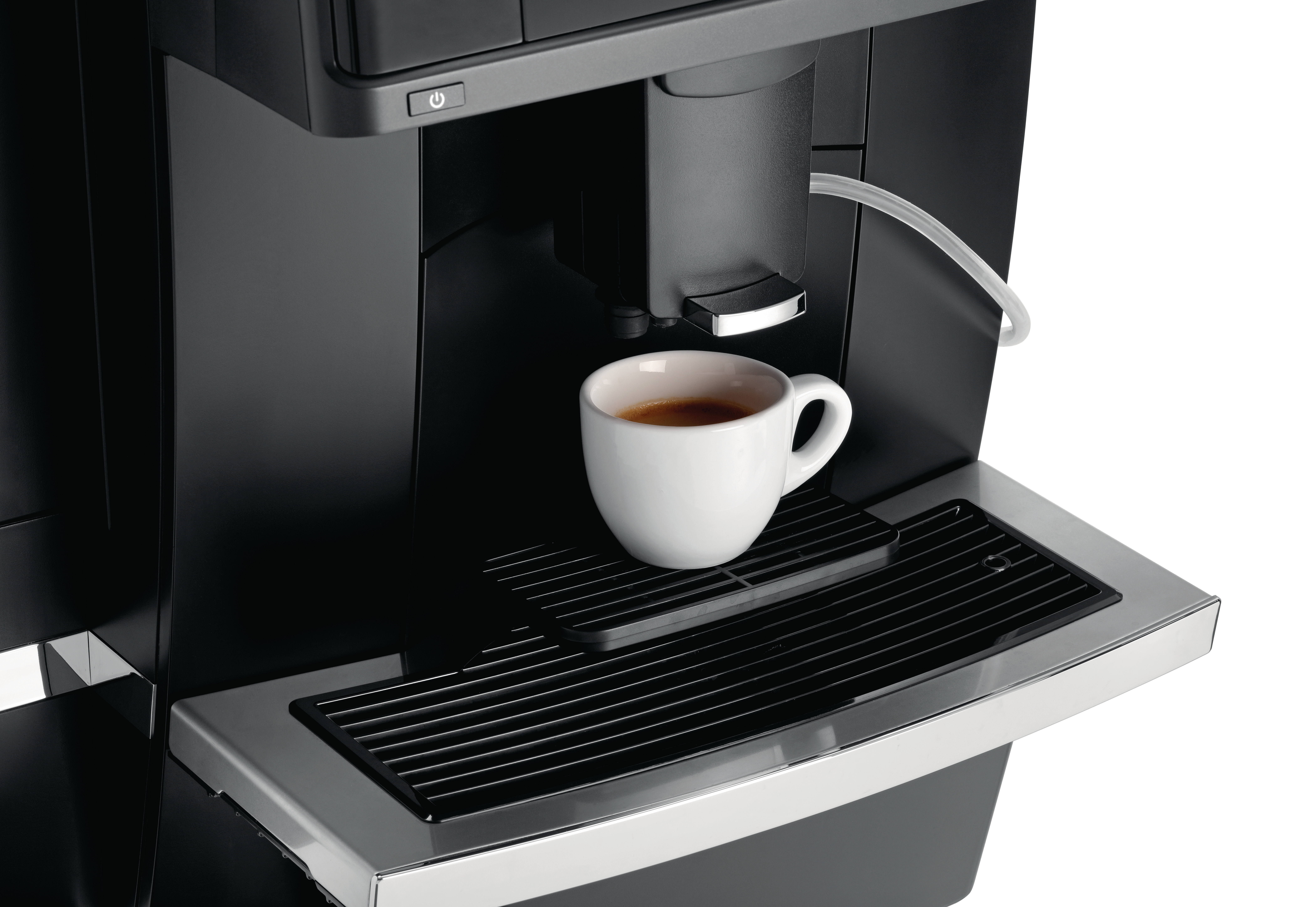 Eine weiße Espressotasse steht auf einem Tropfblech einer Kaffeemaschine.