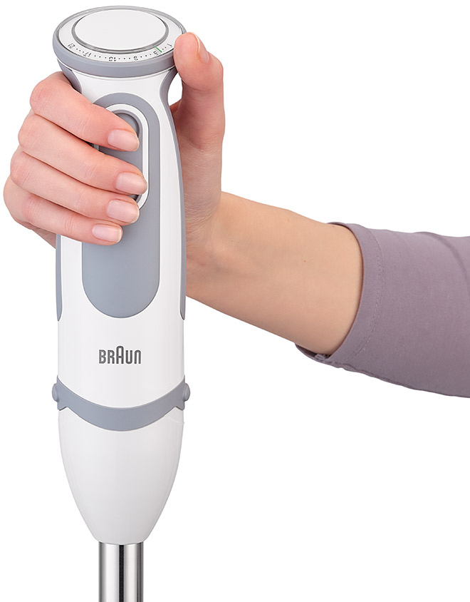 A hand holds a white and gray Braun immersion blender. The brand name is visible.