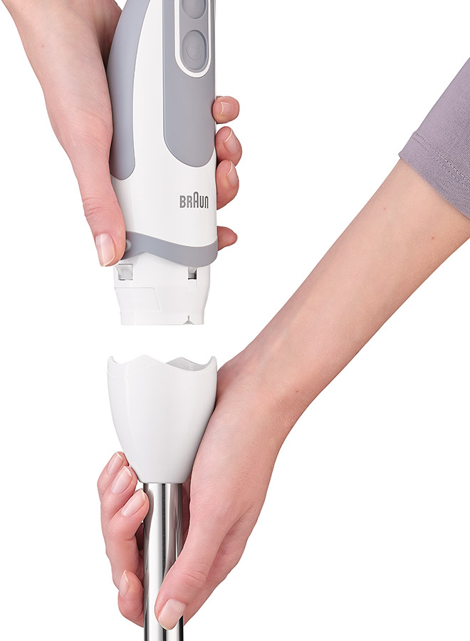 Hands assembling a white and gray Braun hand blender. White background.