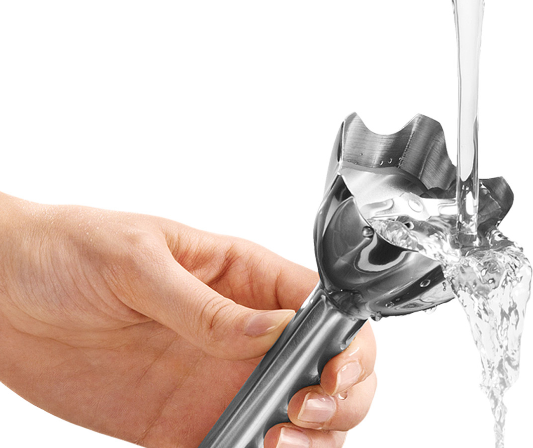 A hand is holding a blender head under running water, with water flowing onto it.