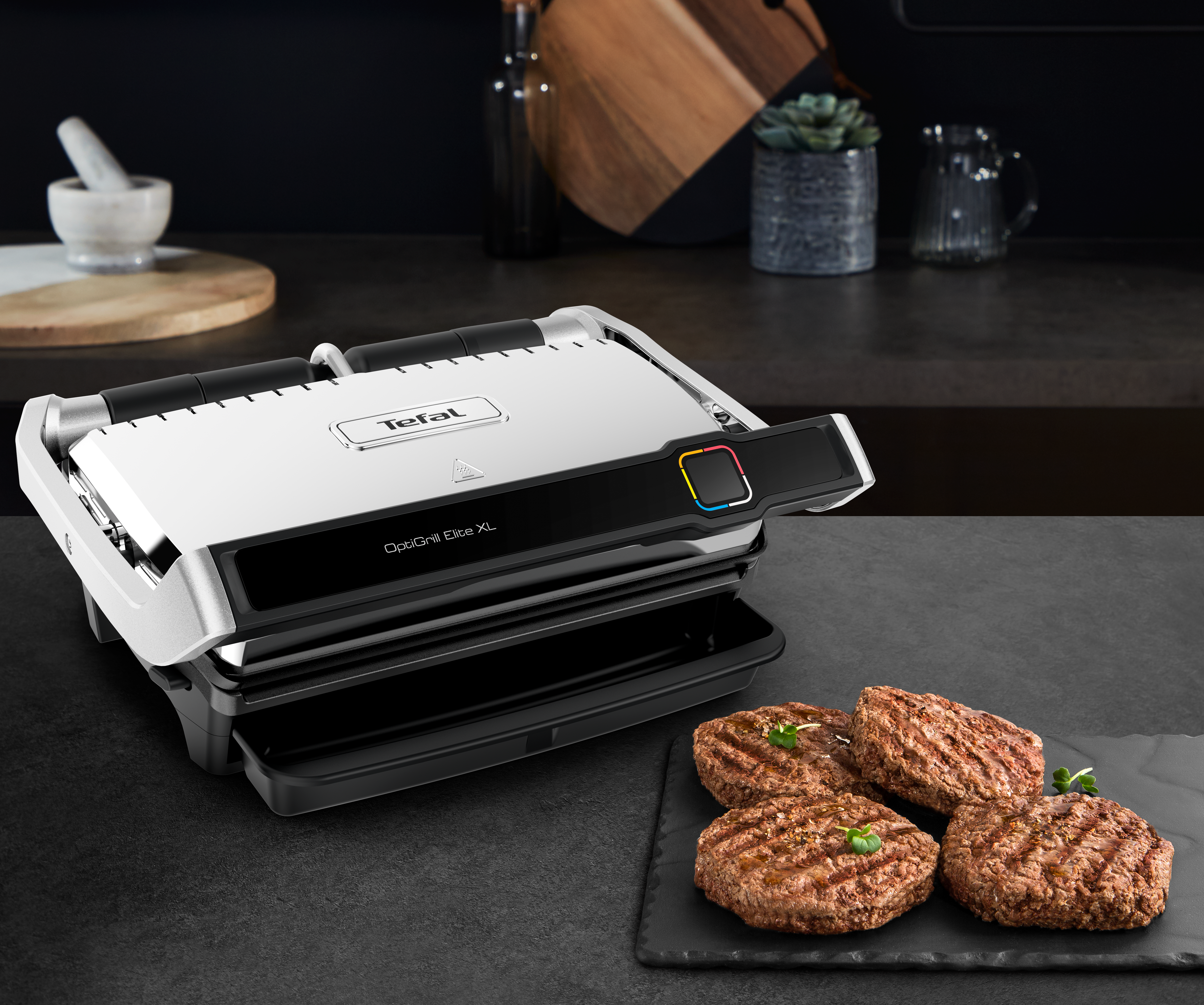 Griglia Tefal con hamburger su una superficie nera.