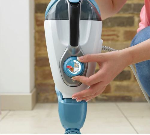 A person's hand adjusting a dial on a blue and white steam mop. The dial is in focus.