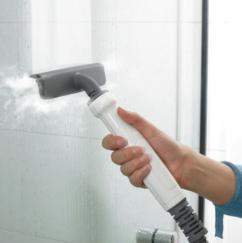A hand using a steam cleaner on a glass surface.