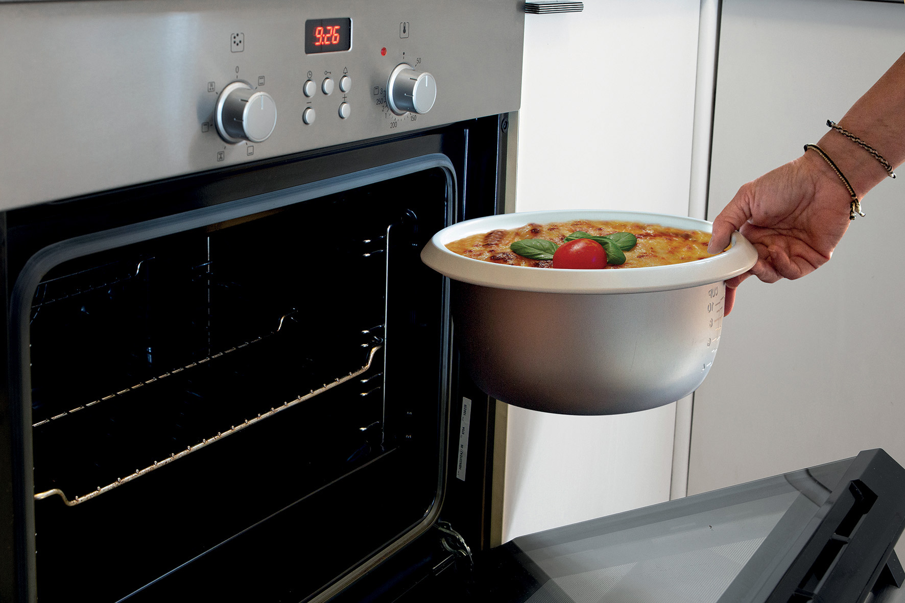 Une personne sortant un plat de nourriture du four, dans un cadre de cuisine.