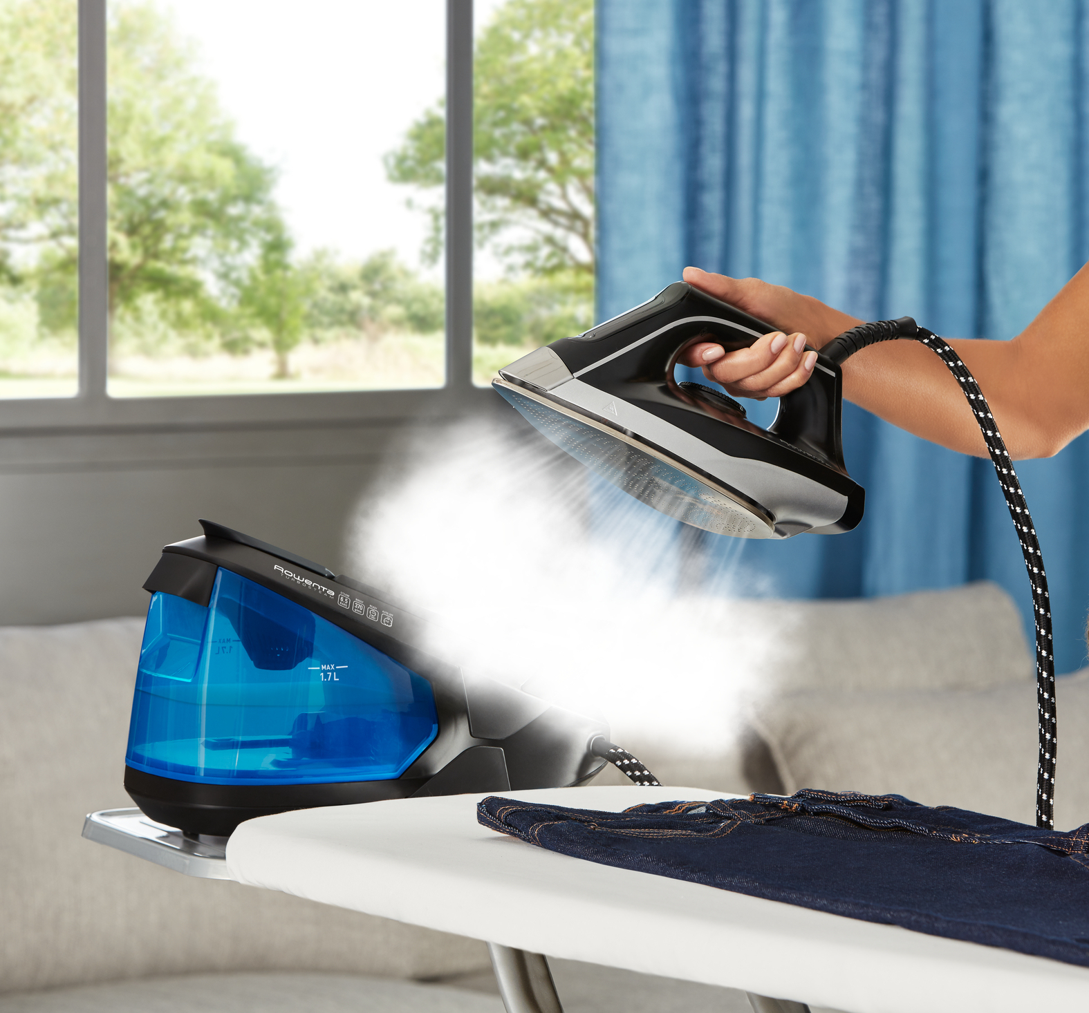 Una persona planchando un vaquero azul oscuro en una tabla de planchar, vapor visible.