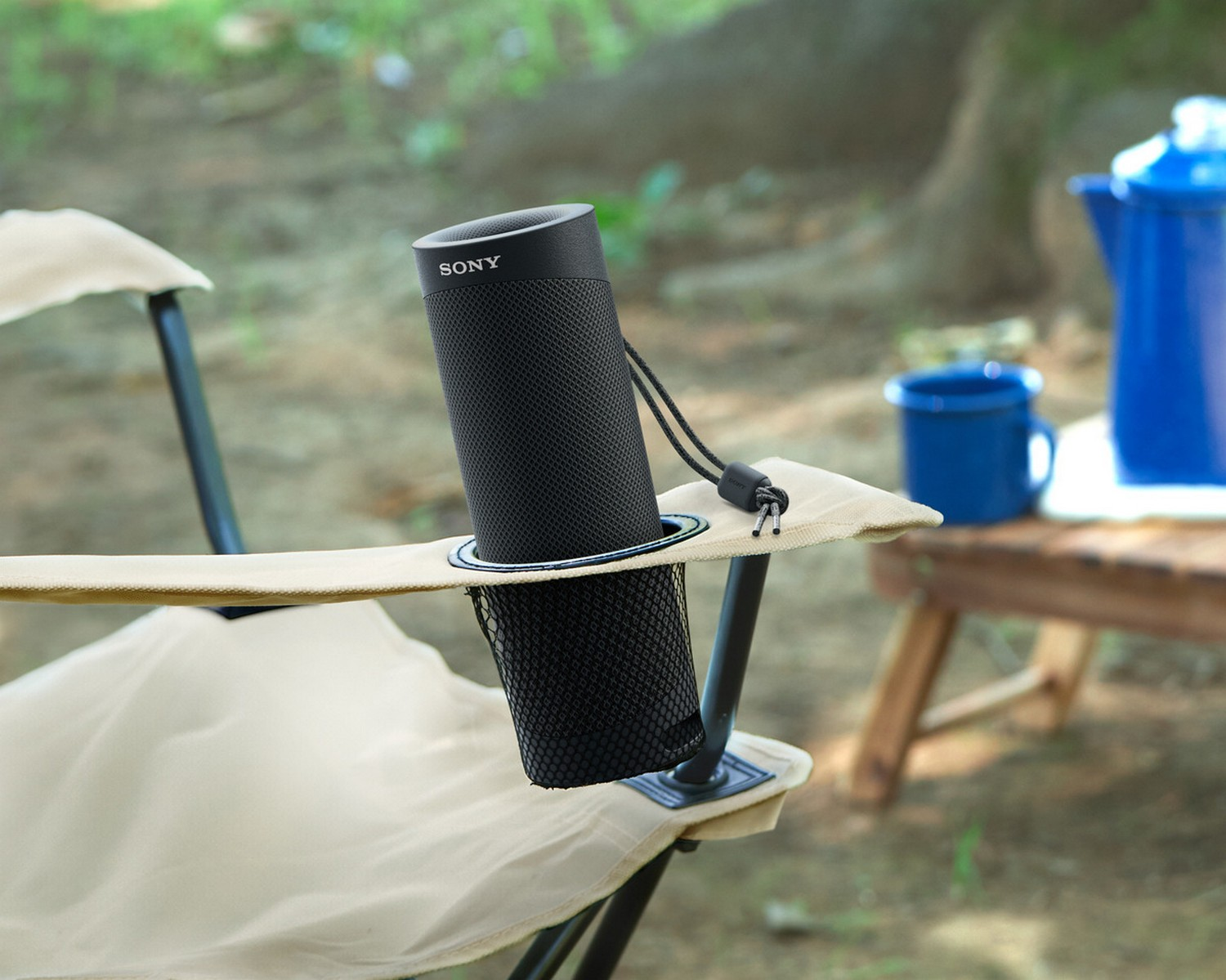 Altavoz Sony negro en un portavasos de silla, con taza y tetera azules.