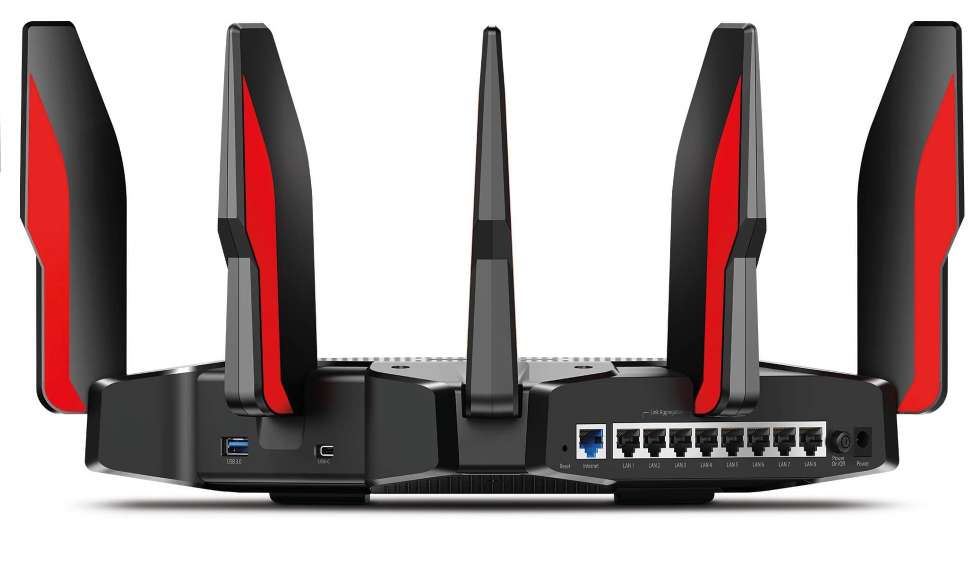 Fekete és piros router antennákkal, fehér háttéren, látható portokkal.