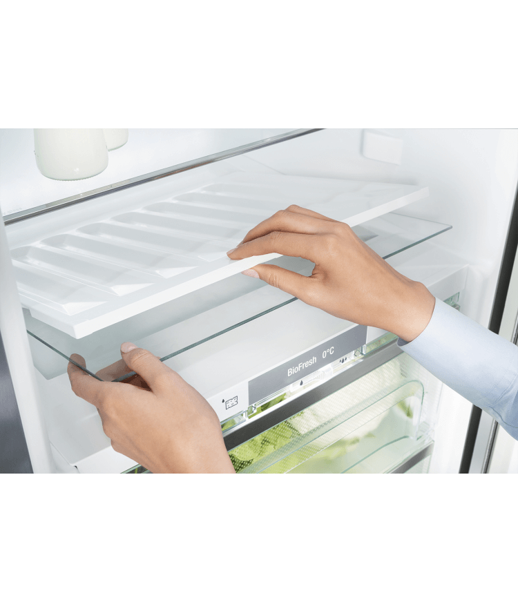 Hands removing a shelf from a refrigerator. The shelf is transparent.