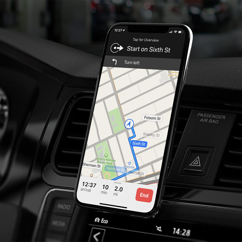 Ein Smartphone zeigt eine Navigationskarte. Das Telefon befindet sich im Armaturenbrett eines Autos.