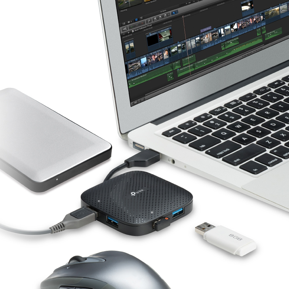 Laptop külső merevlemezzel, USB hubbal és pendrive-val, fehér felületen.