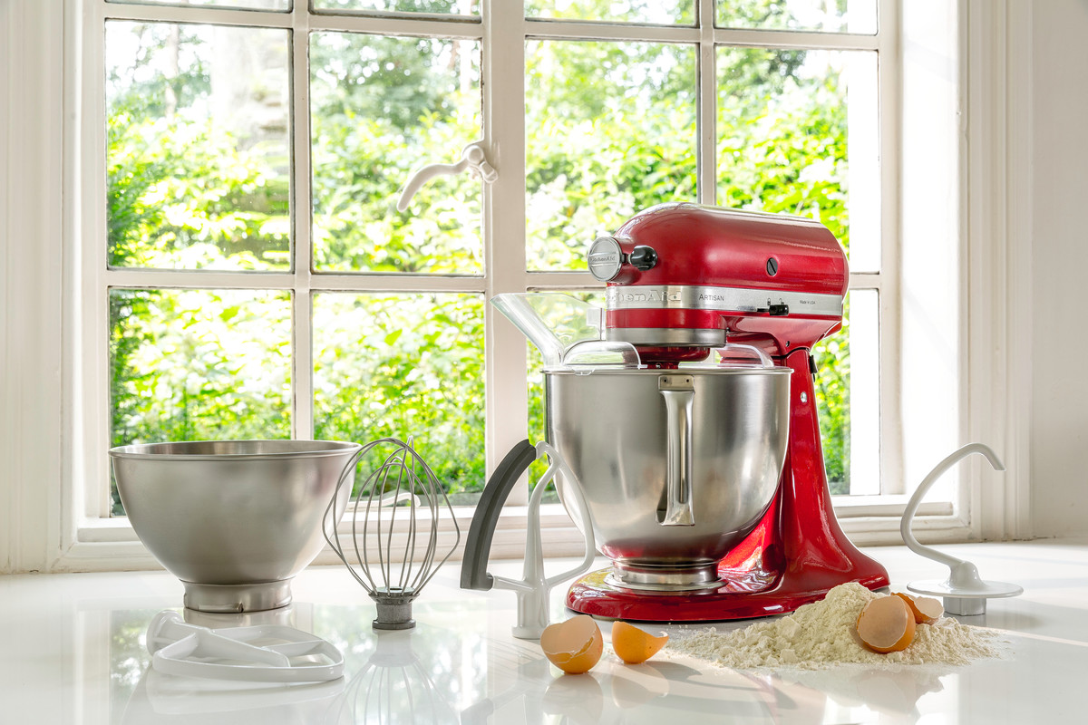 Roter KitchenAid Küchenmixer mit Zubehör, Mehl und Eiern.