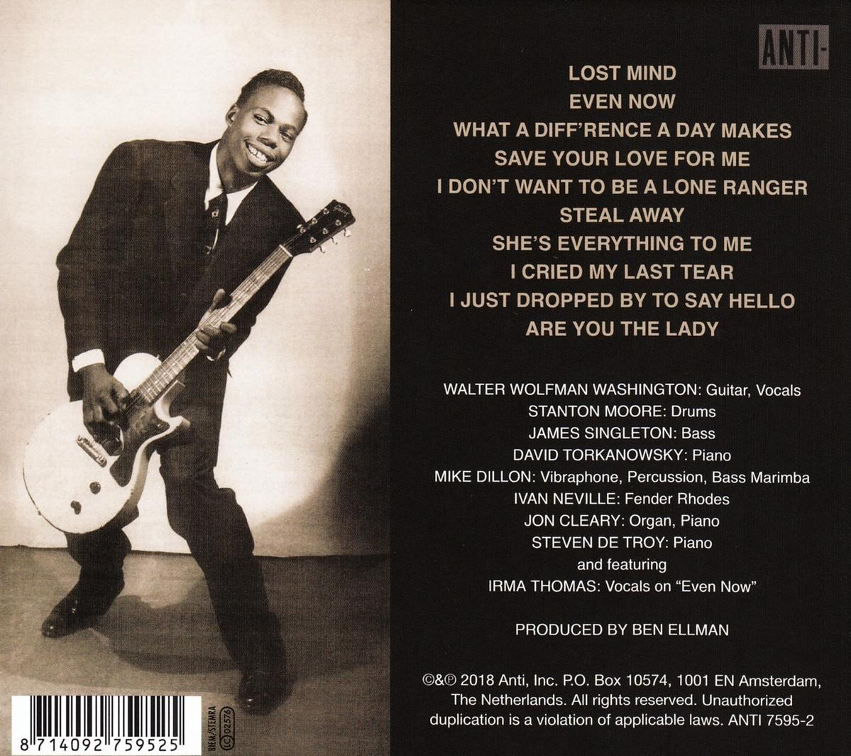 Een man in pak speelt een witte gitaar. De achtergrond heeft tekst over het album en het Anti-logo.