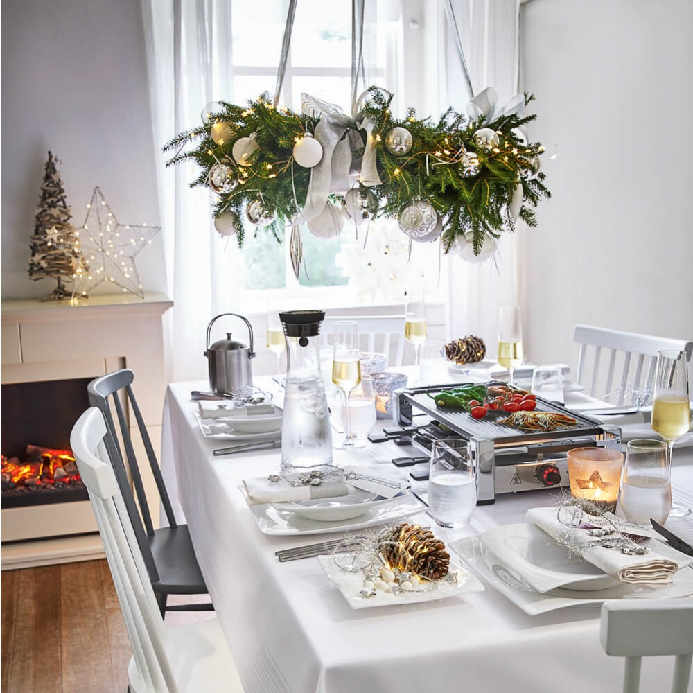 Weihnachtstisch, Dekorationen, Kerzen, Essen und weiße Tischdecke.