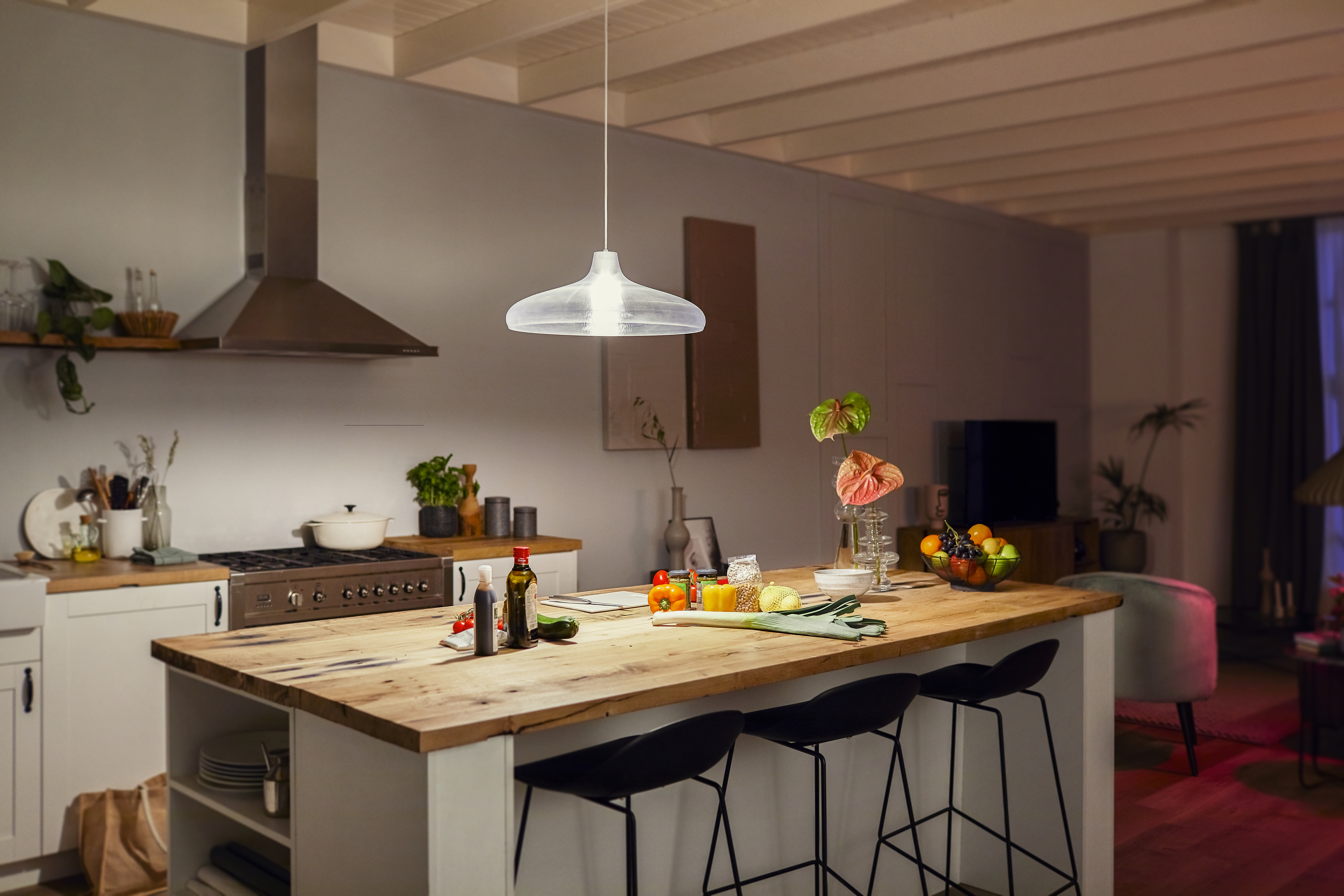 Moderne Küche mit Holzinsel, weißen Schränken und Edelstahlgeräten. Über der Insel hängt eine Lampe.