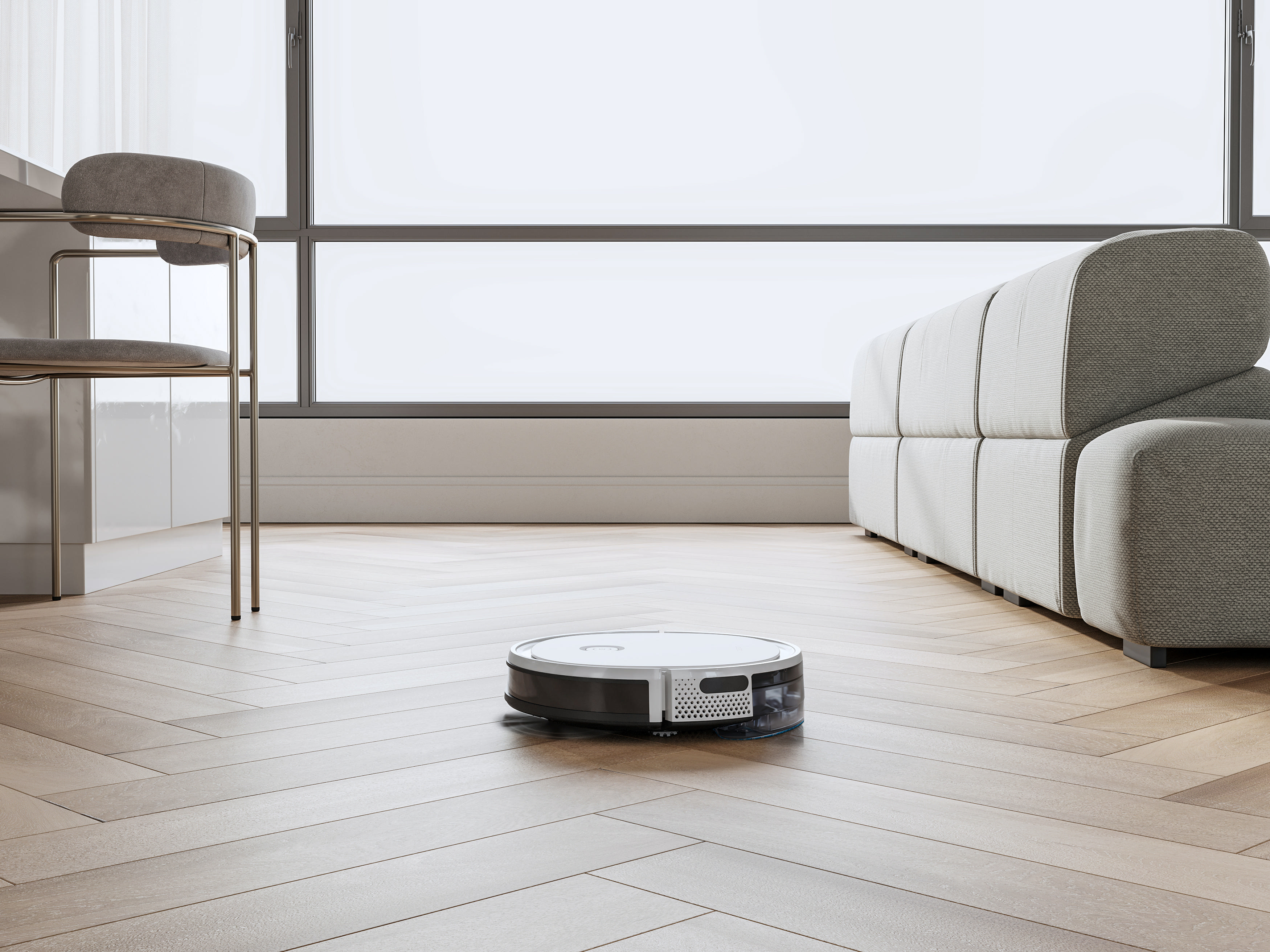 Ein Roboterstaubsauger reinigt einen Holzboden. Ein graues Sofa und ein Stuhl stehen neben einem großen Fenster.