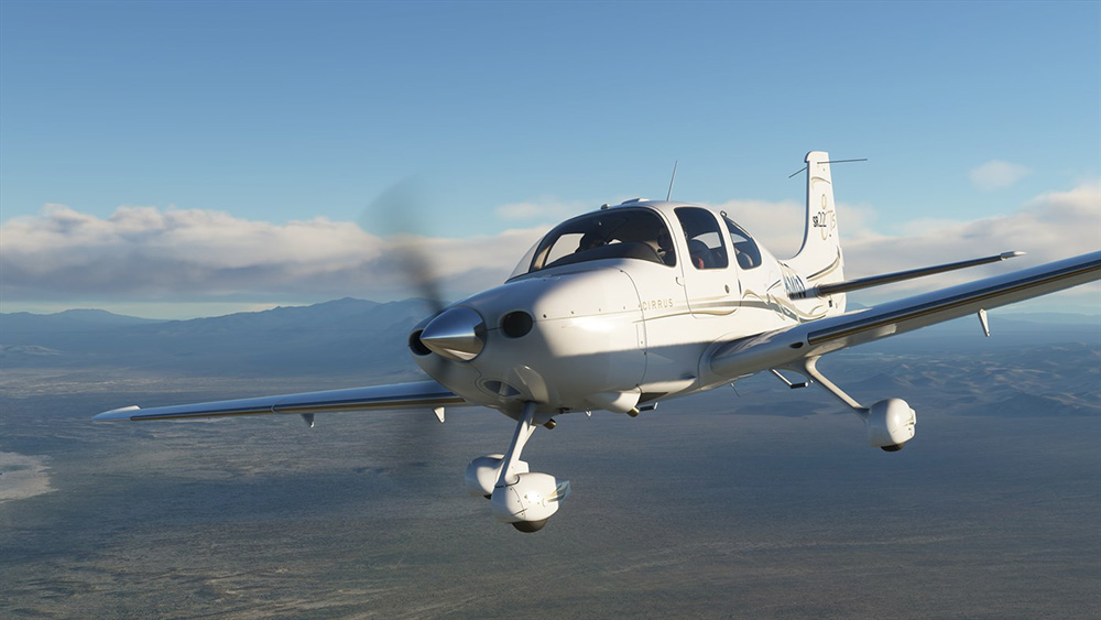 Un avion blanc et gris volant dans le ciel. L'avion a une hélice et le mot CIRRUS est imprimé.