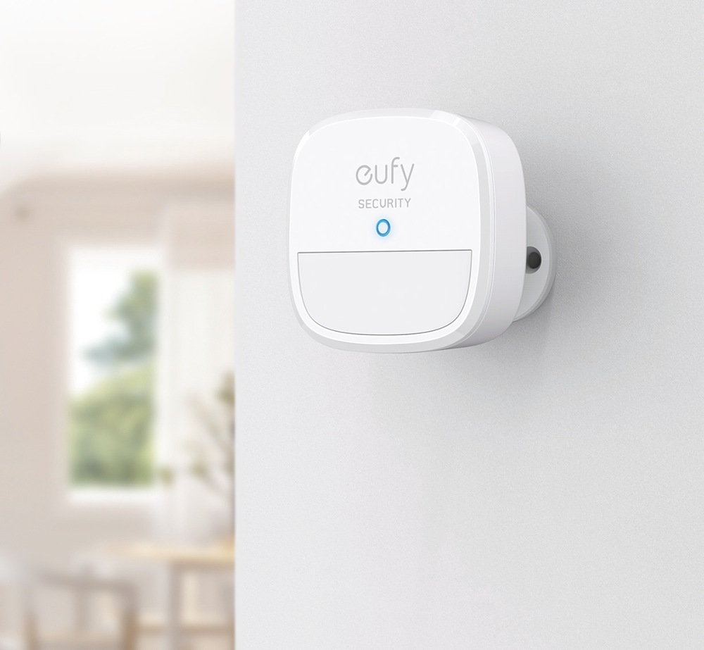White security device, eufy brand, mounted on a wall, with a blue light.
