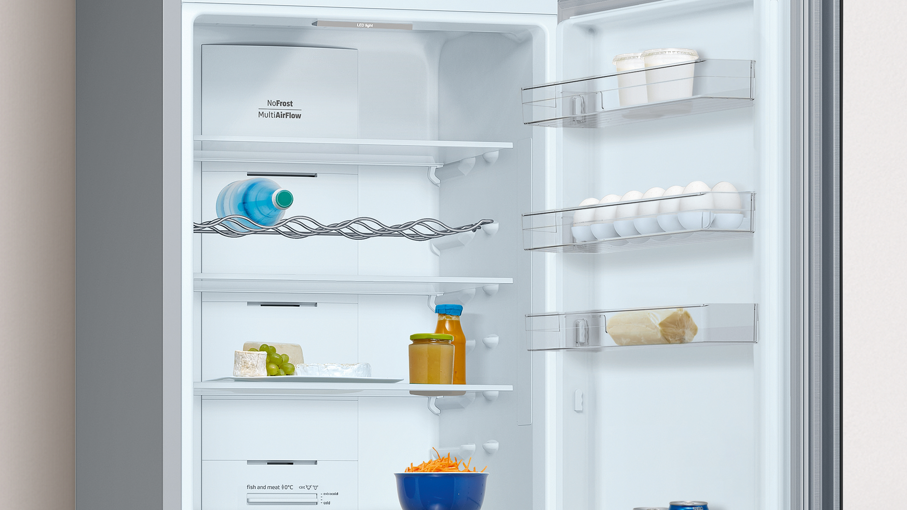 Interior de refrigerador con estantes, alimentos y una botella de agua.