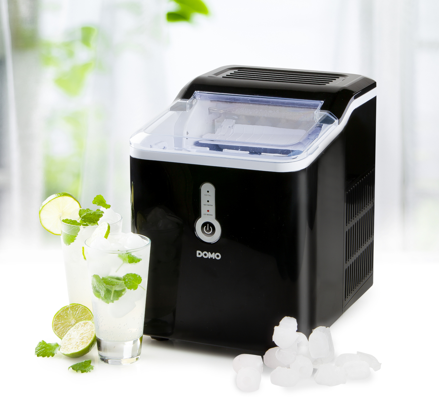 Black ice maker with two glasses of cocktails, mint and lime, on white.