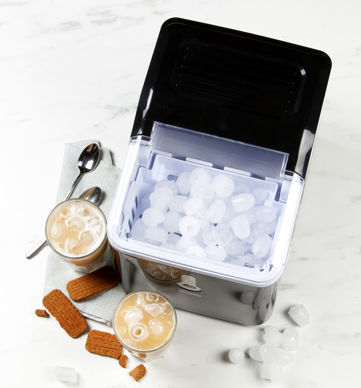Ice machine with ice cubes, two glasses with drinks and cookies. White background.
