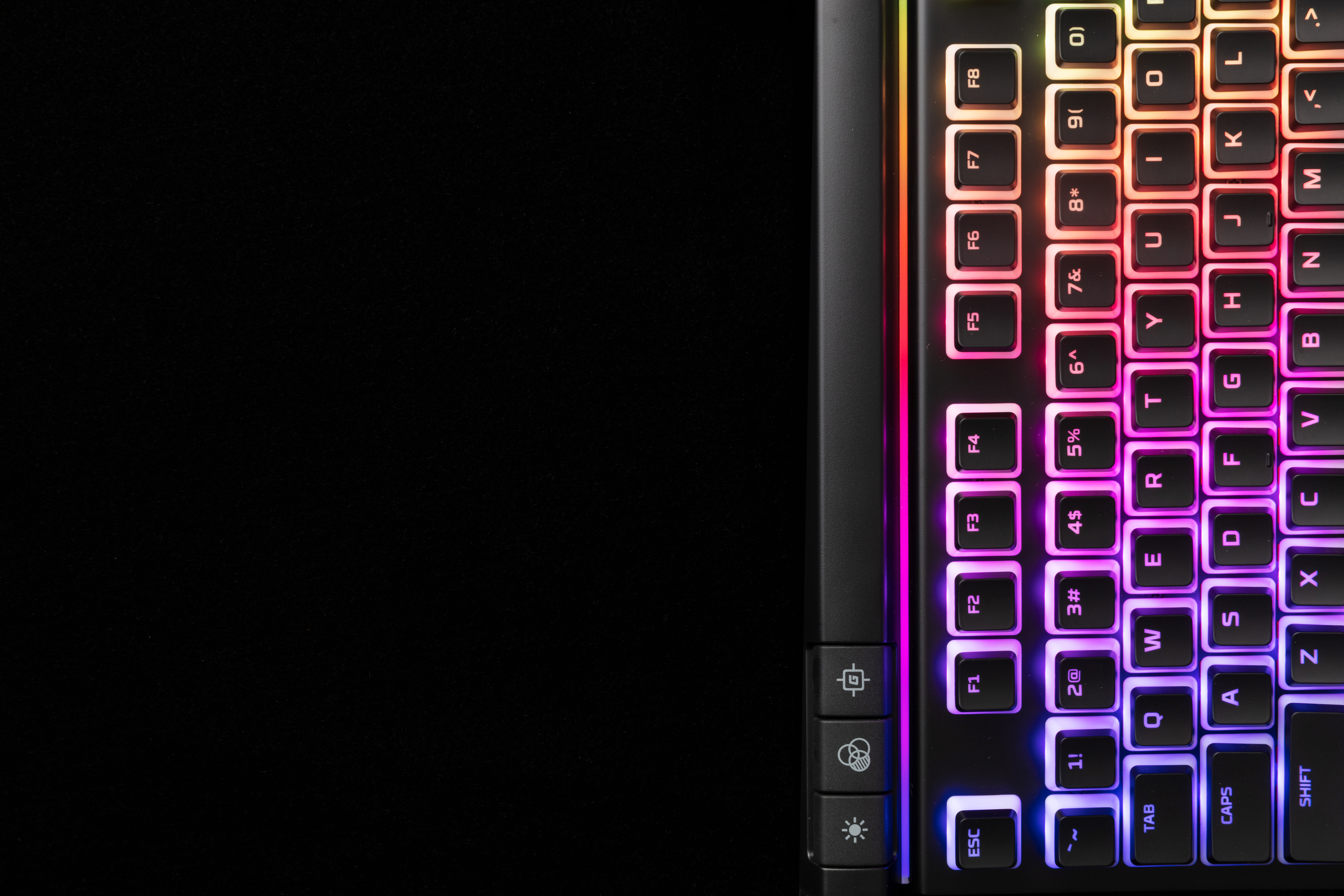 Nahaufnahme einer hintergrundbeleuchteten, regenbogenfarbenen Tastatur. Die Tasten sind hell vor schwarzem Hintergrund beleuchtet.