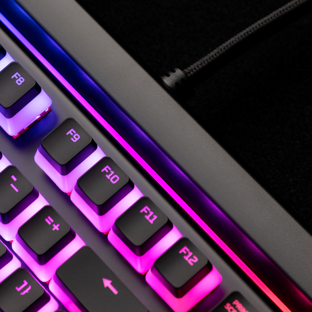 Nahaufnahme einer Tastatur mit schwarzen Tasten, beleuchtet mit pinken und lila Lichtern.