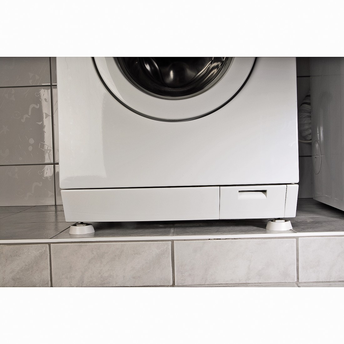 Witte wasmachine op tegels met witte nivelleerpoten.