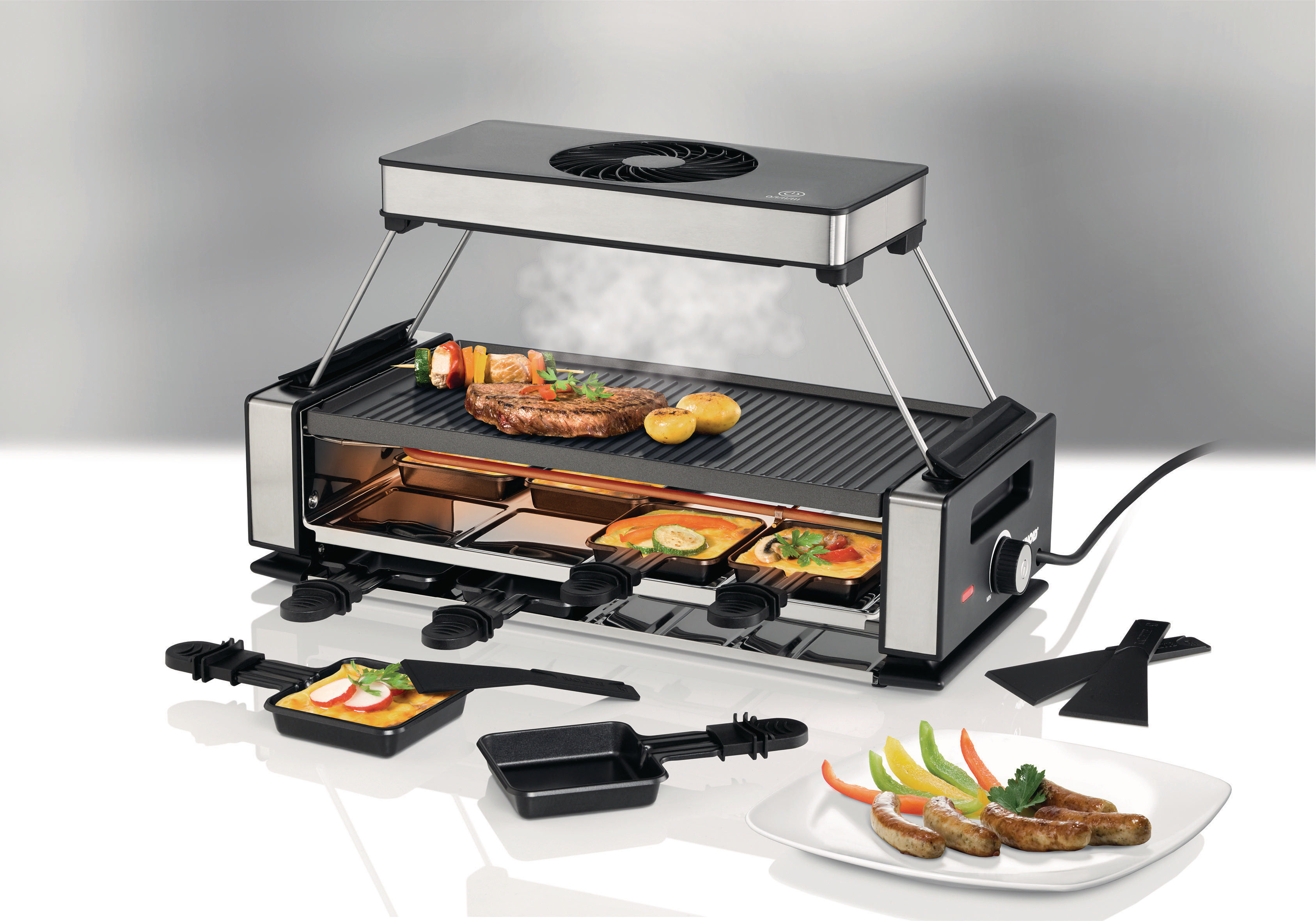 Raclette-Grill mit Essen. Enthält Grill, Pfannen und einen Teller mit Essen. Dampf kommt aus dem Grill.