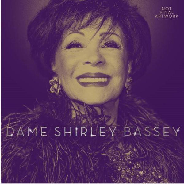 Dame Shirley Bassey lächelt, trägt einen Pelzstola und Ohrringe. Text: Dame Shirley Bassey.