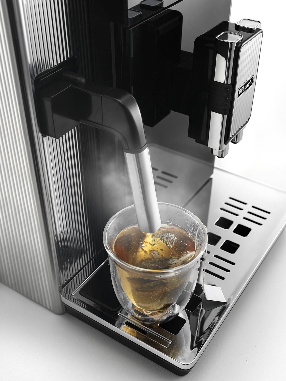 Coffee machine dispensing tea into a clear glass cup.