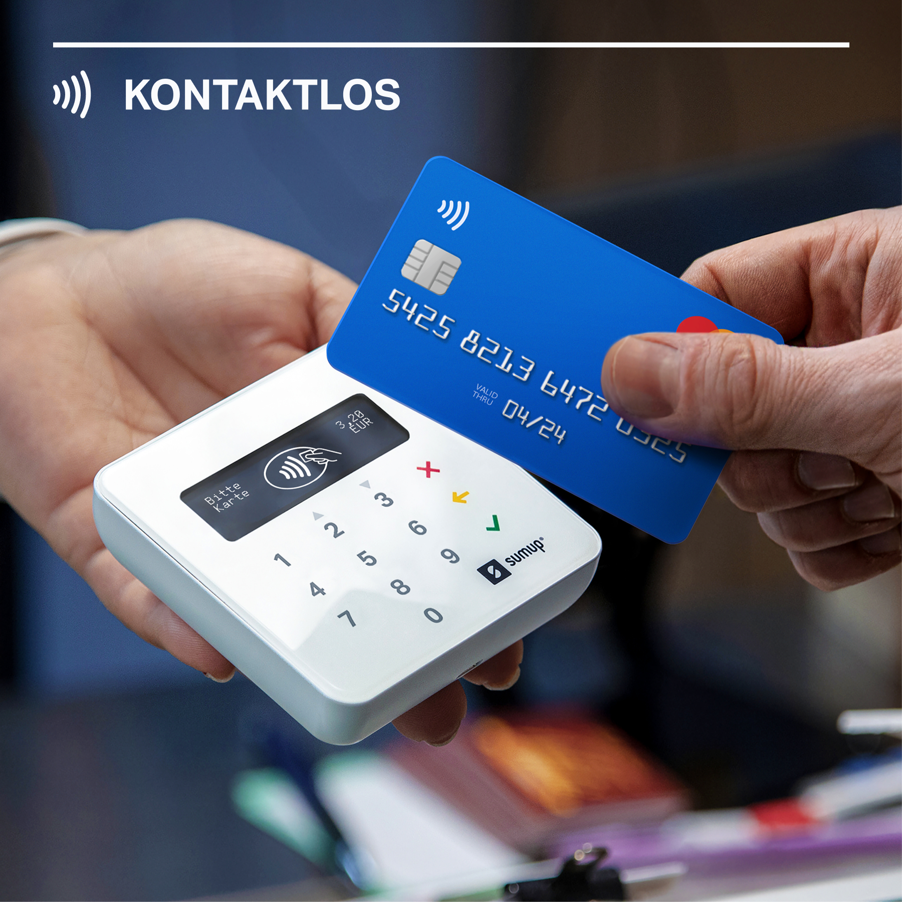 Person bezahlt kontaktlos mit blauer Karte über weißes Zahlungsterminal.