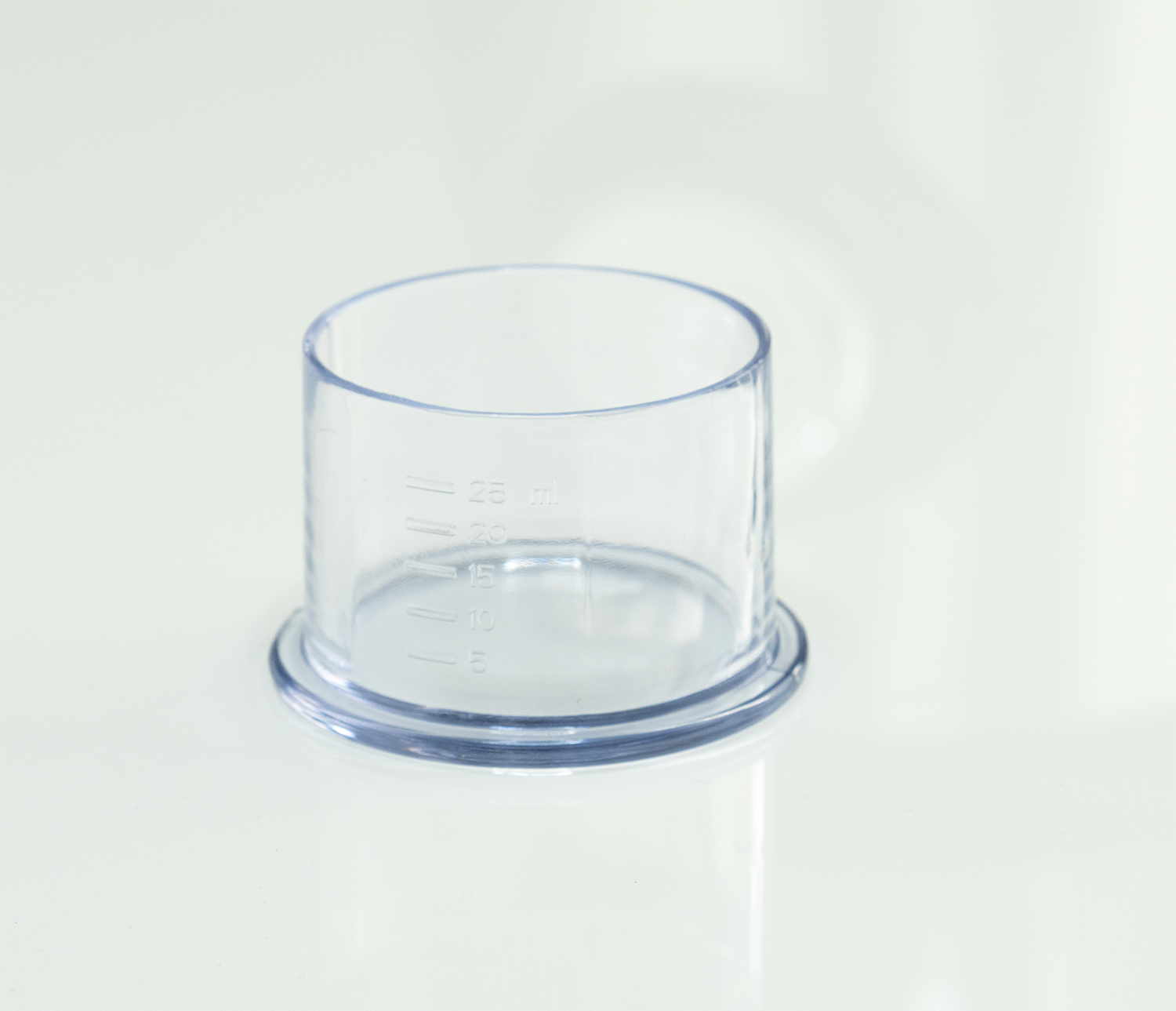 Transparante maatbeker met markeringen voor milliliters op een wit oppervlak.