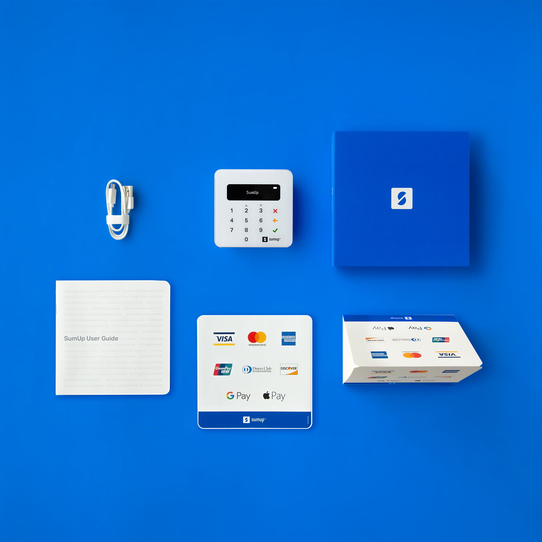 Ein SumUp-Zahlungssystem-Setup mit Kartenleser, Kabel, Benutzerhandbuch und einer blauen Box auf blauem Hintergrund.