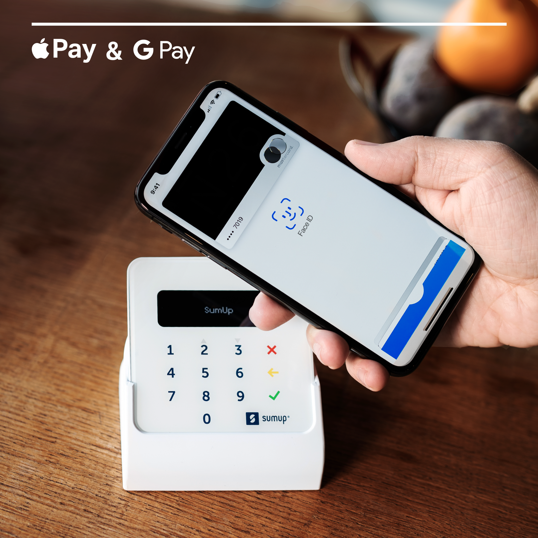 Telefon über SumUp-Gerät zur Zahlung gehalten. Apple Pay- und G Pay-Logos. Holztisch.