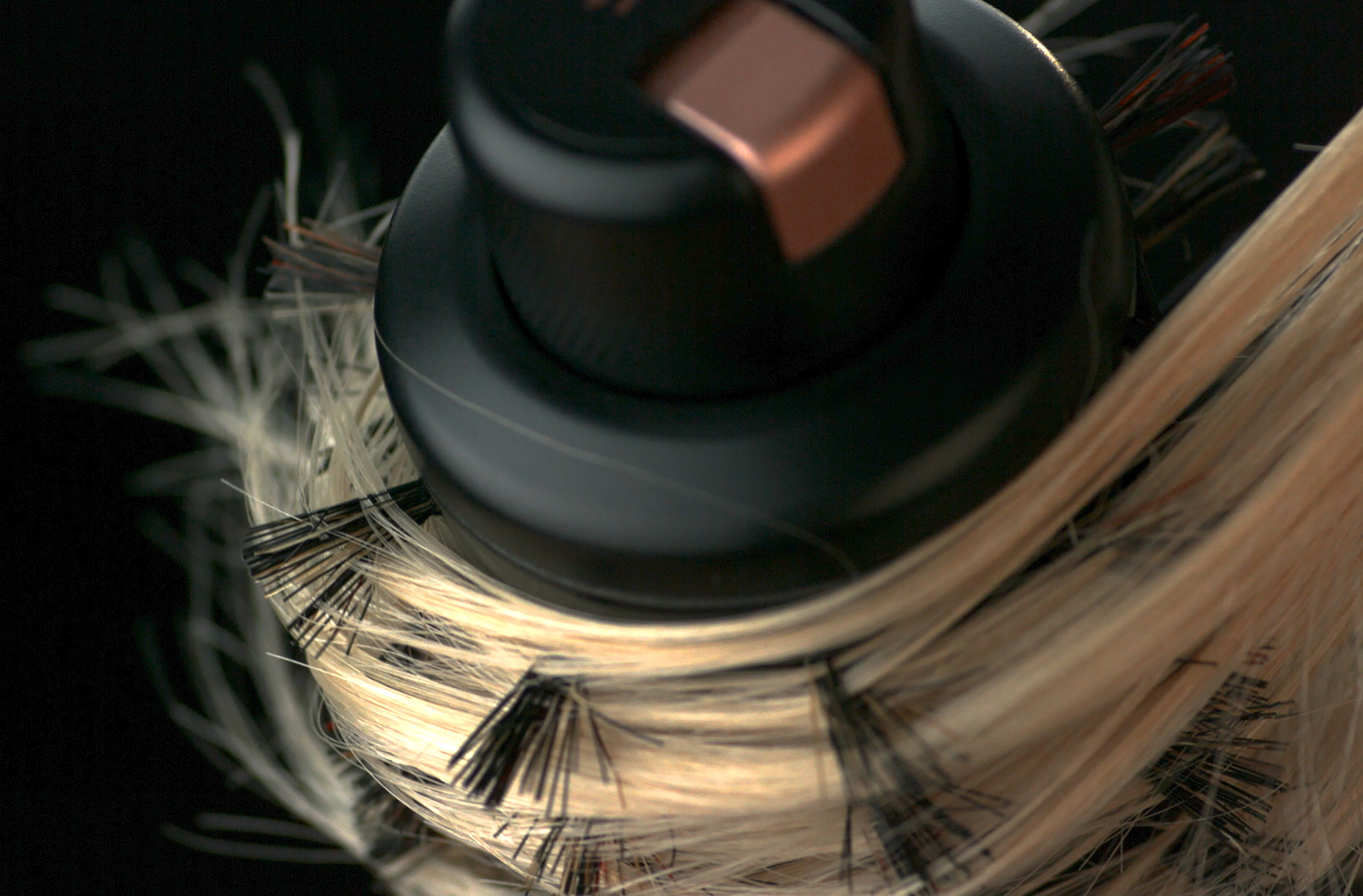 Haare und Haarlockenwickler in Nahaufnahme. Schwarzer Lockenwickler, blondes Haar.