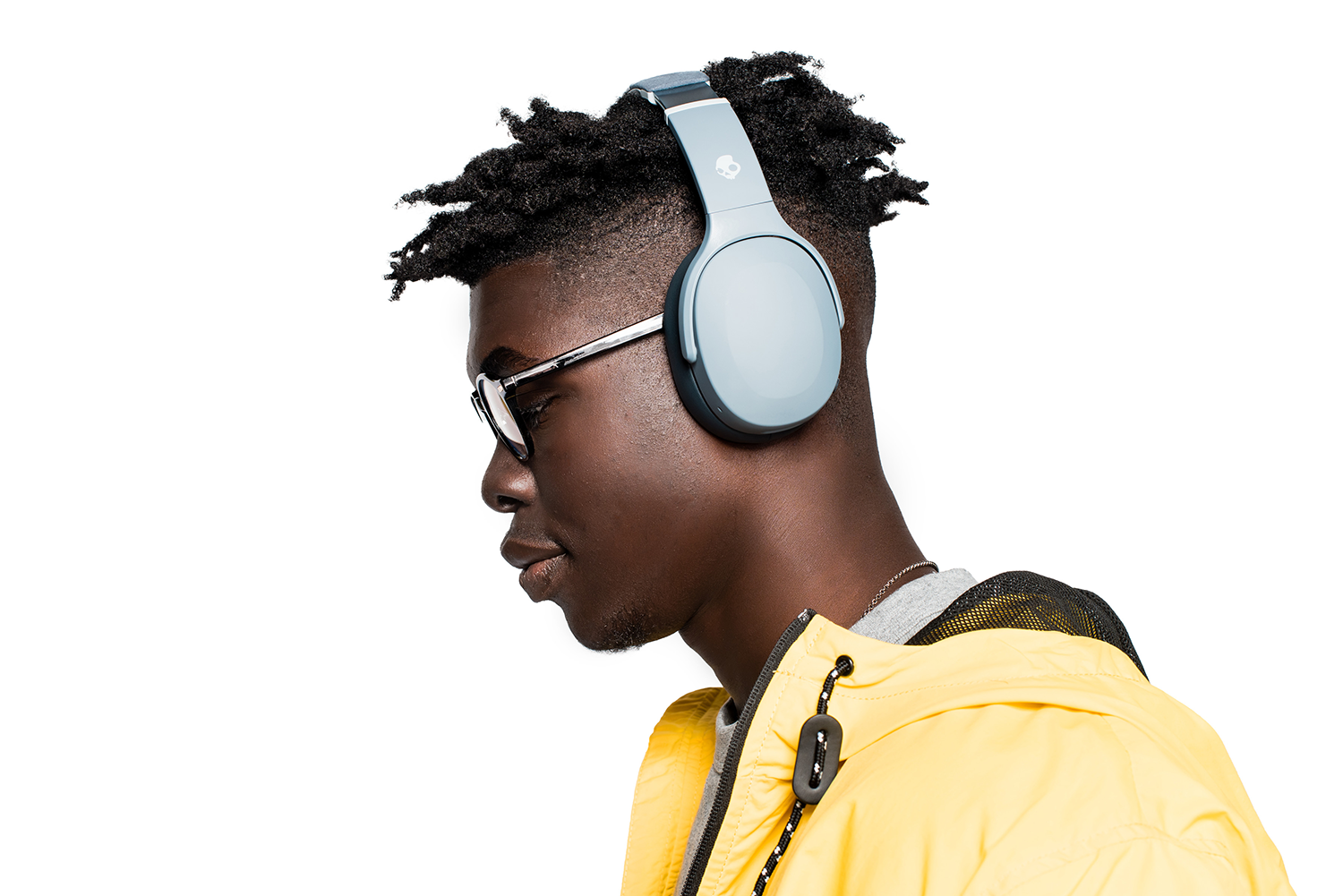 A young man with glasses and headphones, wearing a yellow jacket. White background.